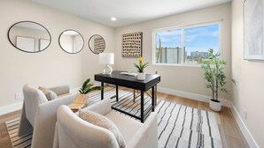 A modern living room with a sofa, a coffee table, a potted plant, and artwork on the walls. - Stunning Views in Bankers Hill! (San Diego)