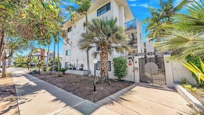A modern building with a gated entrance, a palm tree, and a sidewalk. - Stunning Views in Bankers Hill! (San Diego)
