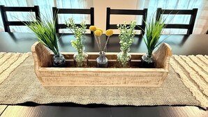 A wooden tray with vases containing plants and flowers, placed on a woven mat. - Refuge on Trinity. Boho Farmhouse, Game Room, Fire Pit (Waxahachie)