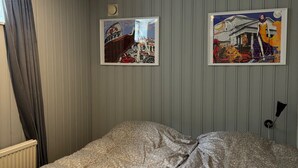 A bedroom with a bed, a ceiling light, a radiator, and two framed pictures on the wall. - Apartment downstairs in my house. Short walking distance to commuter train. (Stockholm)