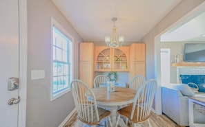 A dining area with a round table, white chairs, and a chandelier. - Cozy Coastal Cottage - 1615 New River Inlet Rd. (North Topsail Beach)