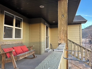 Eine überdachte Veranda mit einer Holzbank und einem Metallgeländer.