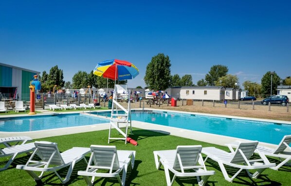 A swimming pool with white lounge chairs and a colorful umbrella.