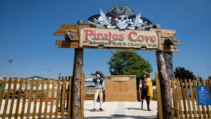 Une enseigne en bois sur laquelle est inscrit : « Pirates Cove Adventure Golf & Climbing Wall ».