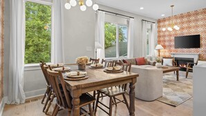 Un coin repas avec une table et des chaises en bois, un canapé, une cheminée et un téléviseur fixé au mur.
