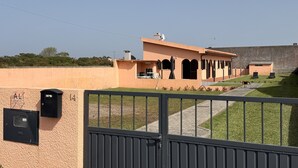 A building with a beige exterior, a gated entrance, and a paved pathway leading to a seating area.