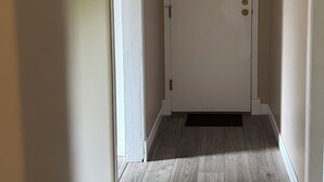 Ein Flur mit Holzboden, einer weißen Tür und beige gestrichenen Wänden.