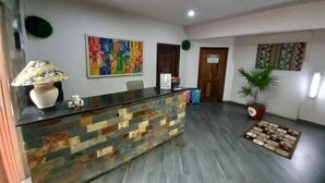 A reception area with a reception desk, a potted plant, and a colorful abstract painting on the wall.