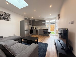 Um apartamento moderno com sala de estar, cozinha e lavanderia.