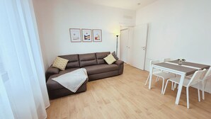 A modern living room with a brown sofa, a white table, and a door in the background. - The Lake House Cernobbio -  Village Center, Walk to Lake (Cernobbio)