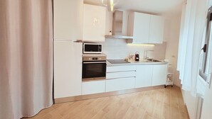 A modern kitchen with white cabinets, a microwave, oven, and a hanging light fixture. - The Lake House Cernobbio -  Village Center, Walk to Lake (Cernobbio)