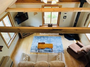 Ein Zimmer mit hohen Decken, einer hölzernen Bank, einem Sofa und einem Teppich.