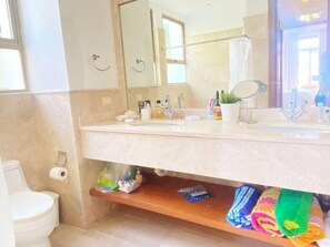 Ein Badezimmer mit einem Doppelwaschbecken, einem Spiegel, einem Handtuchhalter und einem Ablagebereich für Toilettenartikel.