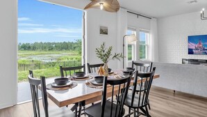 En matplats med utsikt över ett grönskande landskap, en modern hänglampa och en platt-TV på väggen.