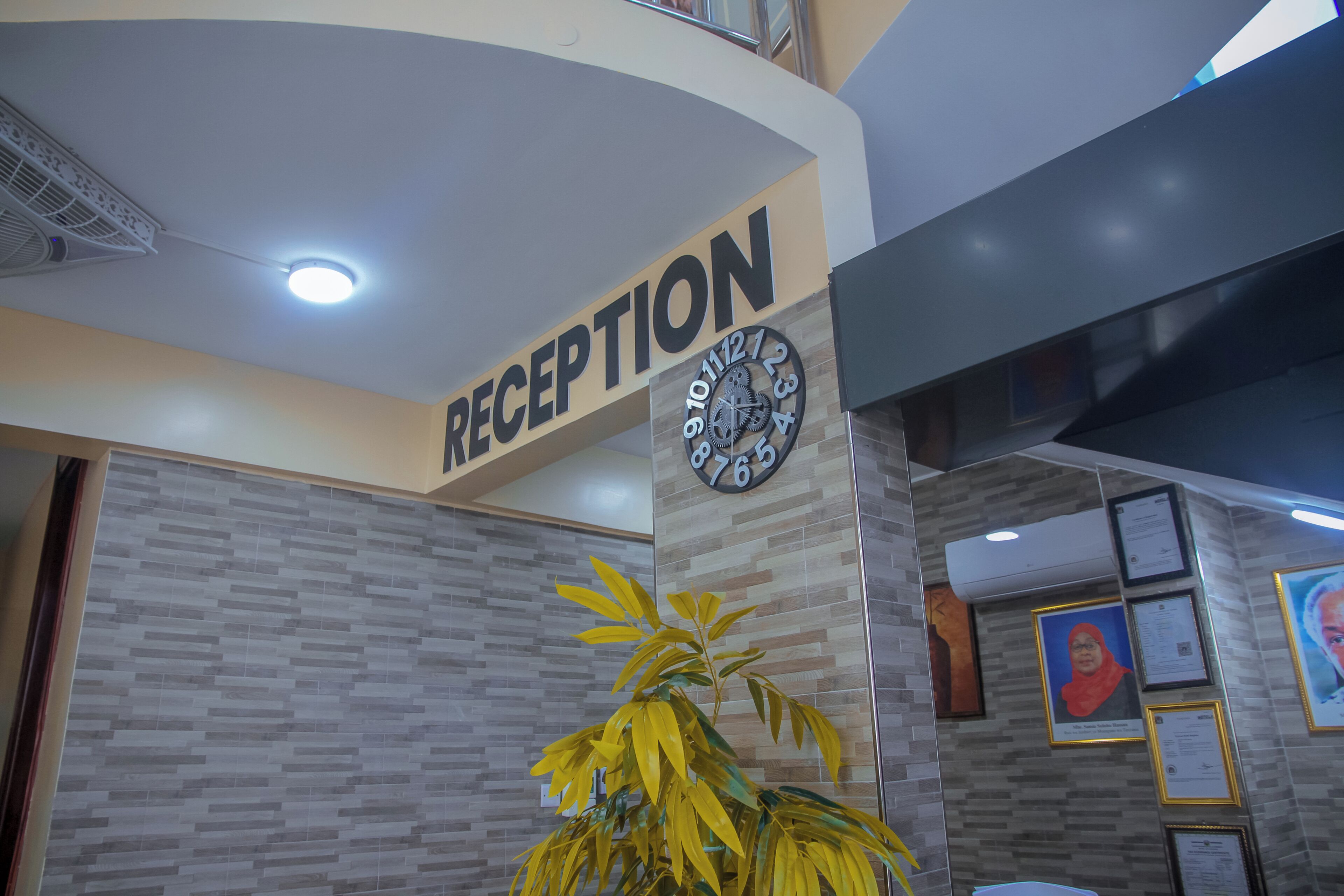 Un espace d’accueil avec une horloge, une enseigne indiquant « RÉCEPTION », et des certificats encadrés accrochés au mur.