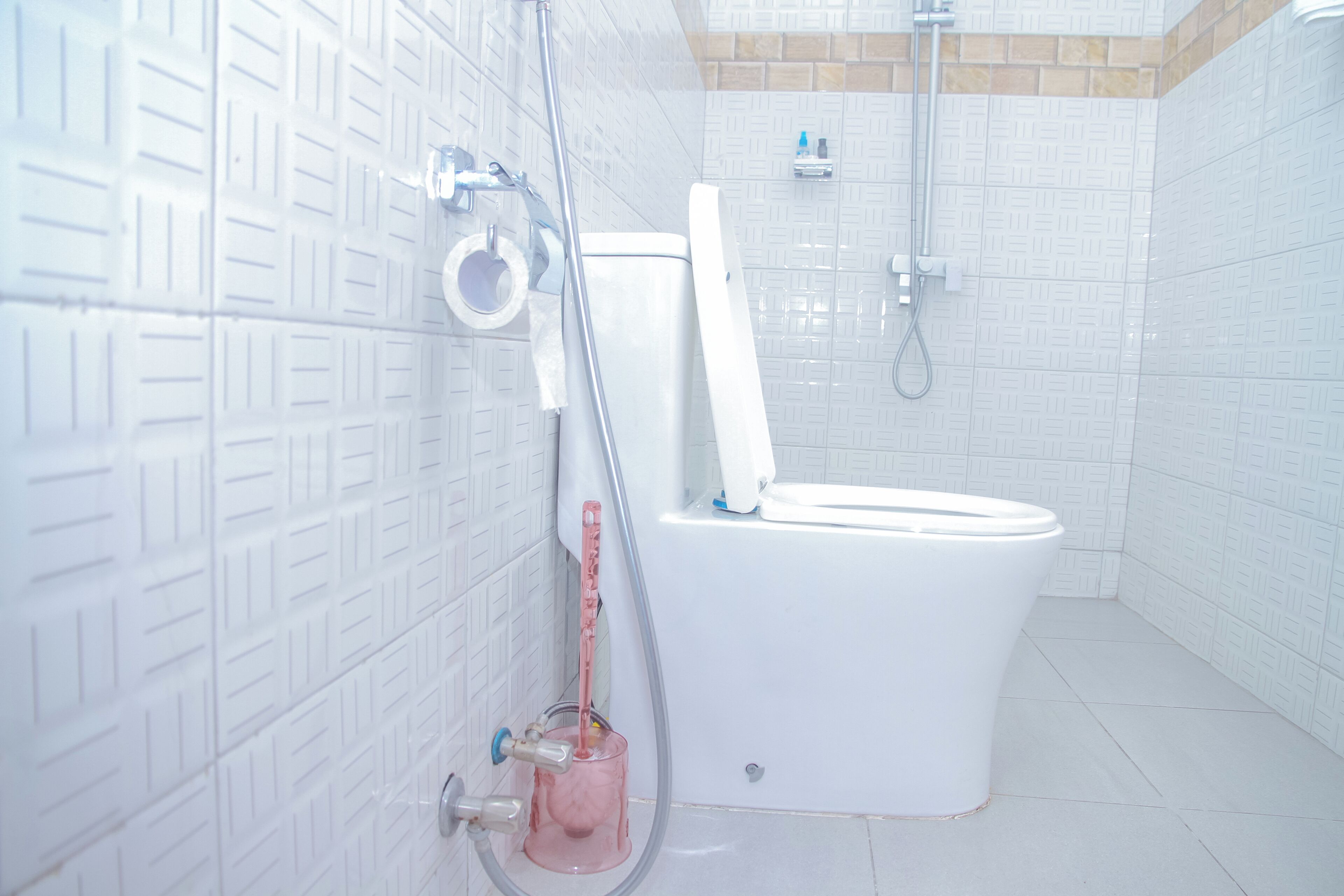 Een badkamer met een wit toilet, een douche en een behang met een patroon.