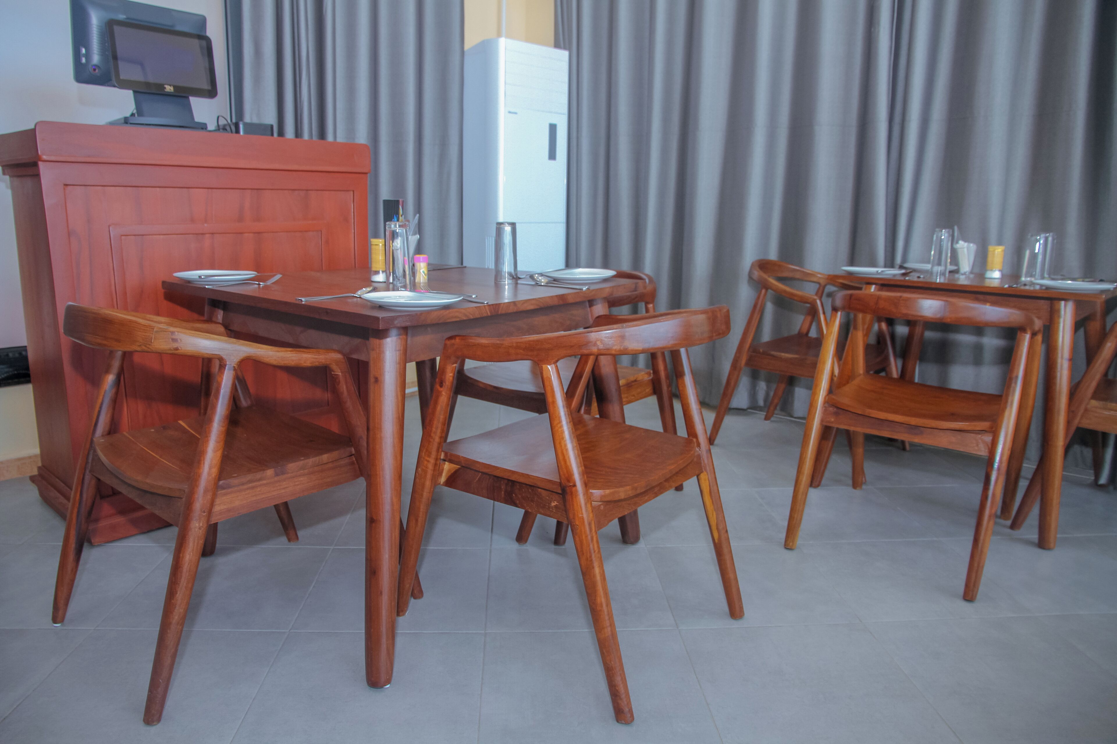 A dining area with a wooden table and chairs, a refrigerator, and a television.