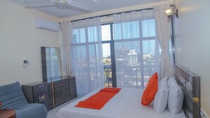 Una habitación de hotel con cama, sofá, televisor y balcón con vistas.