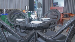 Una mesa redonda para comer con sillas, una máquina expendedora y un televisor al fondo.