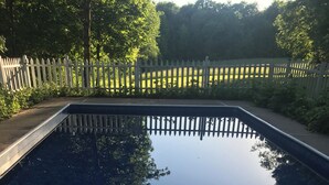Ein rechteckiger Swimmingpool, umgeben von einem weißen Zaun.