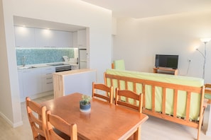 A compact living space with a kitchenette, a dining area, and a sleeping area with a TV. - Apartament Sea View 6F (Portimão)