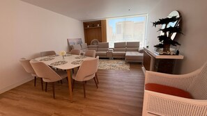 Ein modernes Wohnzimmer mit Esstisch, Sofas, Couchtisch und großem Fenster.