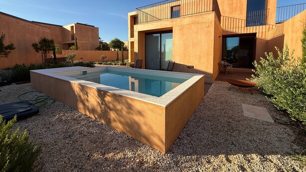 Ein modernes Haus mit Swimmingpool, Sitzgelegenheiten im Freien und einem Balkon.