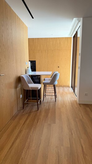 Eine moderne Küche mit Holzschränken, einer weißen Arbeitsplatte und zwei Barhocker.