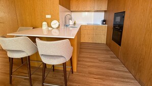 Eine moderne Küche mit Holzschränken, einer weißen Arbeitsplatte und zwei grauen Stühlen.