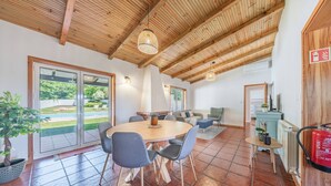 Un'ampia sala da pranzo con un tavolo rotondo, sedie e un soffitto con travi in legno.