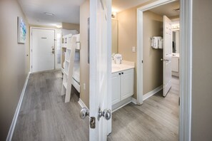 A hallway with a white door, a white shelf unit, and a white cabinet with a mirror. - Island Princess 608🌊Gulf Front🏖️Free Beach Setup (Fort Walton Beach)