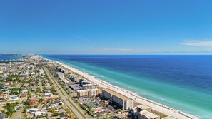 Eine Küstenstadt mit einem langen Strand, Gebäuden und wolkenlosem Himmel.