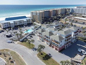 A multi-story hotel with balconies, a swimming pool, and a view of the beach. - Sunset Cottages 4A👙Beach Cottage🐶Pet Friendly (Fort Walton Beach)