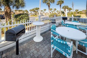 Eine Terrasse im Freien mit weißer und blauer Möbeln, einem Grill und einem weißen Zaun.