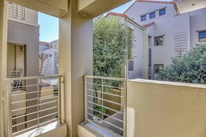 Ein Balkon mit Metallgeländer, Blick auf benachbarte Gebäude und einen Baum.