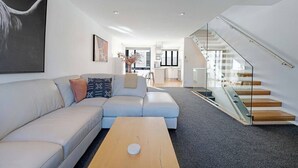 A modern living room with a sofa, a coffee table, and a staircase leading to an upper level.