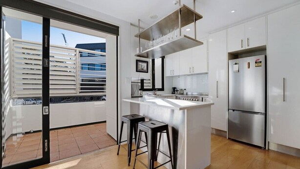 A modern kitchen with a central island, stainless steel appliances, and a view of a building outside.