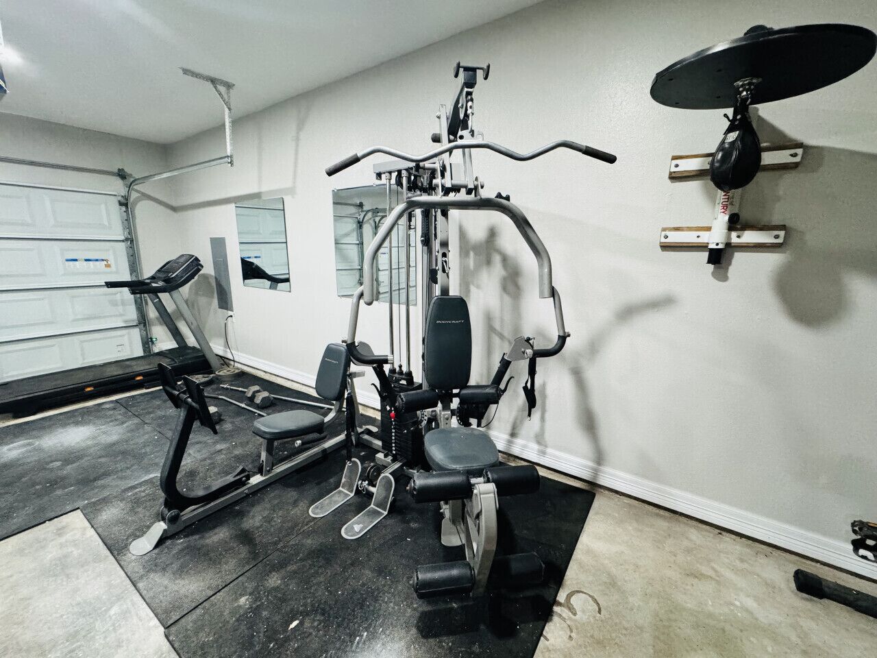 Une salle de sport équipée de matériel d’exercice, avec un miroir et une porte.