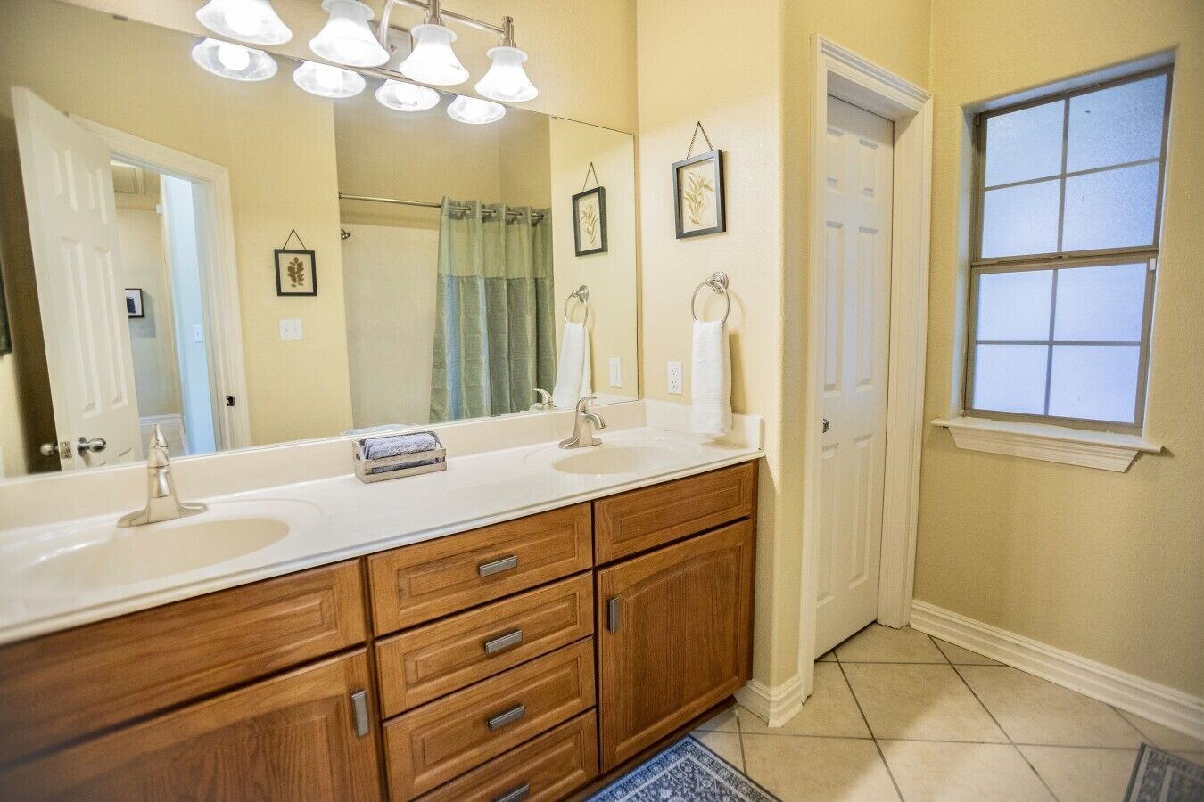 A bathroom with a double sink vanity, a large mirror, and a window.