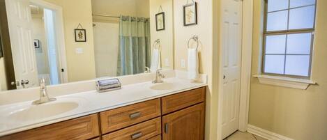 A bathroom with a double sink vanity, a large mirror, and a window.
