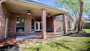 A brick house with a covered patio, a lawn, and a tree. - Where style meets comfort (Orange)