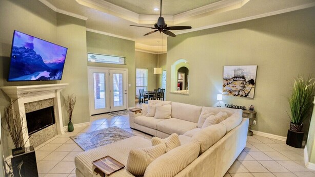 A living room with a fireplace, a sofa, a television, and a ceiling fan. - Where style meets comfort (Orange)