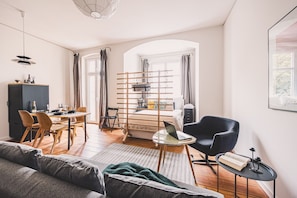 A modern living room with a sofa, dining area, and a bed with a desk. - Diente | Studio | Poznań Jeżyce | Balkon & Kamienica (Poznań)