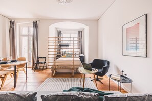 A modern living room with a dining area, a bed with a wooden headboard, a laptop on a small table, and a framed picture on the wall. - Diente | Studio | Poznań Jeżyce | Balkon & Kamienica (Poznań)