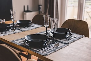 A dining table set with black plates, silverware, and two clear glasses. - Diente | Studio | Poznań Jeżyce | Balkon & Kamienica (Poznań)