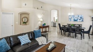 A living room with a dark leather sofa, a coffee table, and a dining area with a table and chairs. - Spacious 4BRFamily Retreat-Pool Minutes to Disney (Davenport)