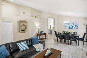 Ein Wohnzimmer mit einem dunkelbraunen Ledersofa, einem Couchtisch und einem Essbereich mit Tisch und Stühlen.