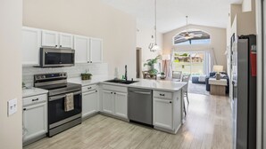 A modern kitchen with white cabinetry, stainless steel appliances, and a central island. - Spacious 4BRFamily Retreat-Pool Minutes to Disney (Davenport)