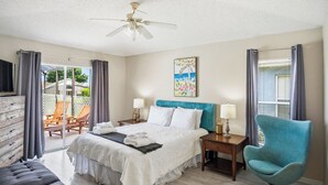 A hotel room with a bed, a chair, a desk, a ceiling fan, and a painting on the wall. - Spacious 4BRFamily Retreat-Pool Minutes to Disney (Davenport)