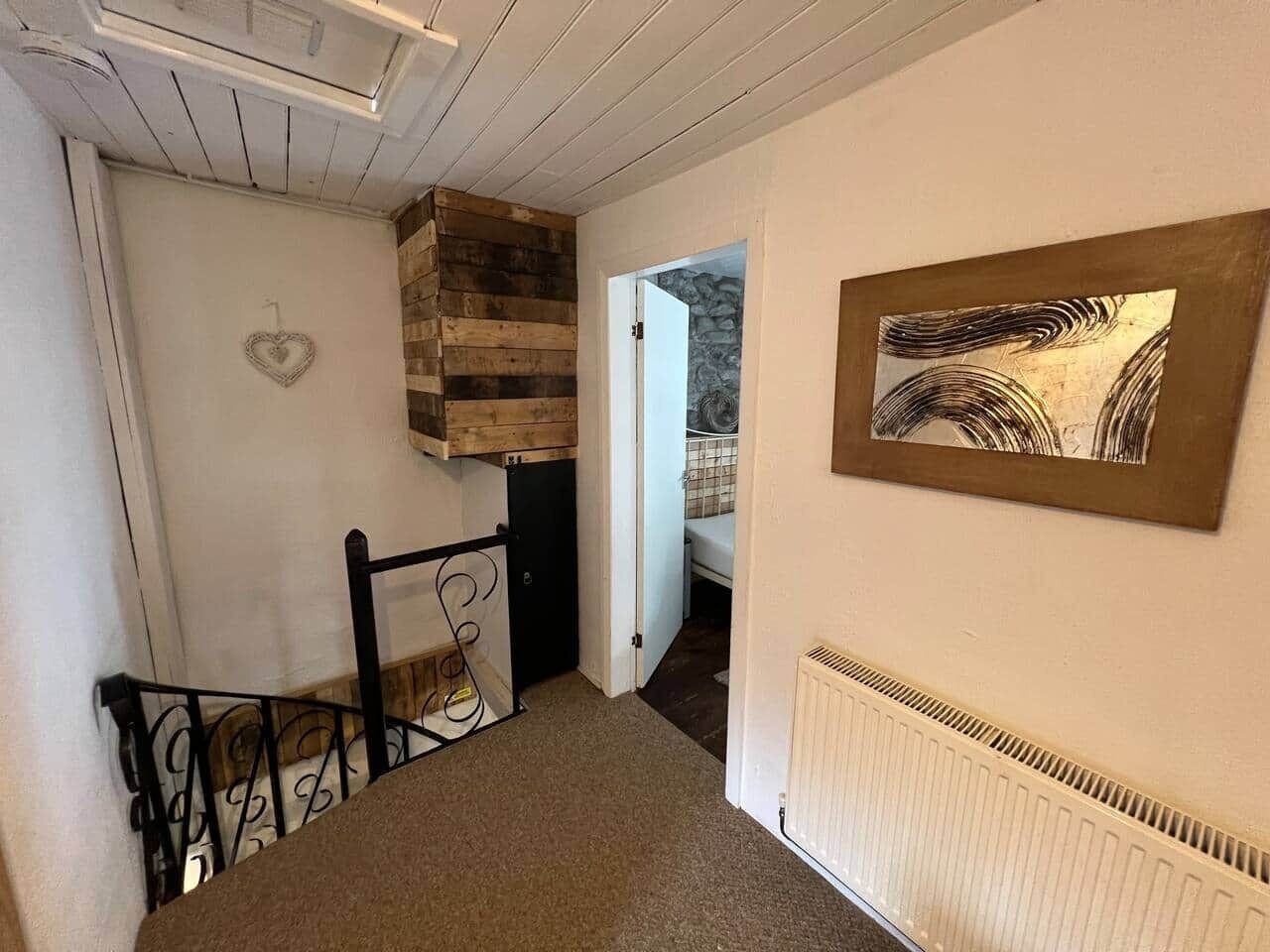Un escalier avec une rampe en métal, un tableau accroché au mur et un radiateur.